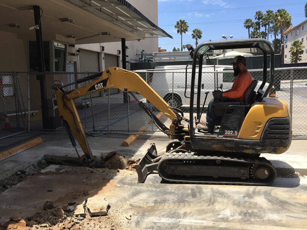 Excavator performing trenching work at a commercial building construction site
