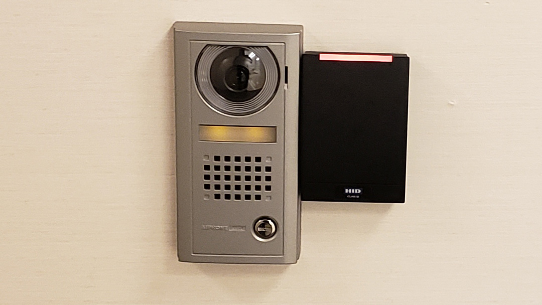 Wall-mounted video intercom and card access reader at a building entrance