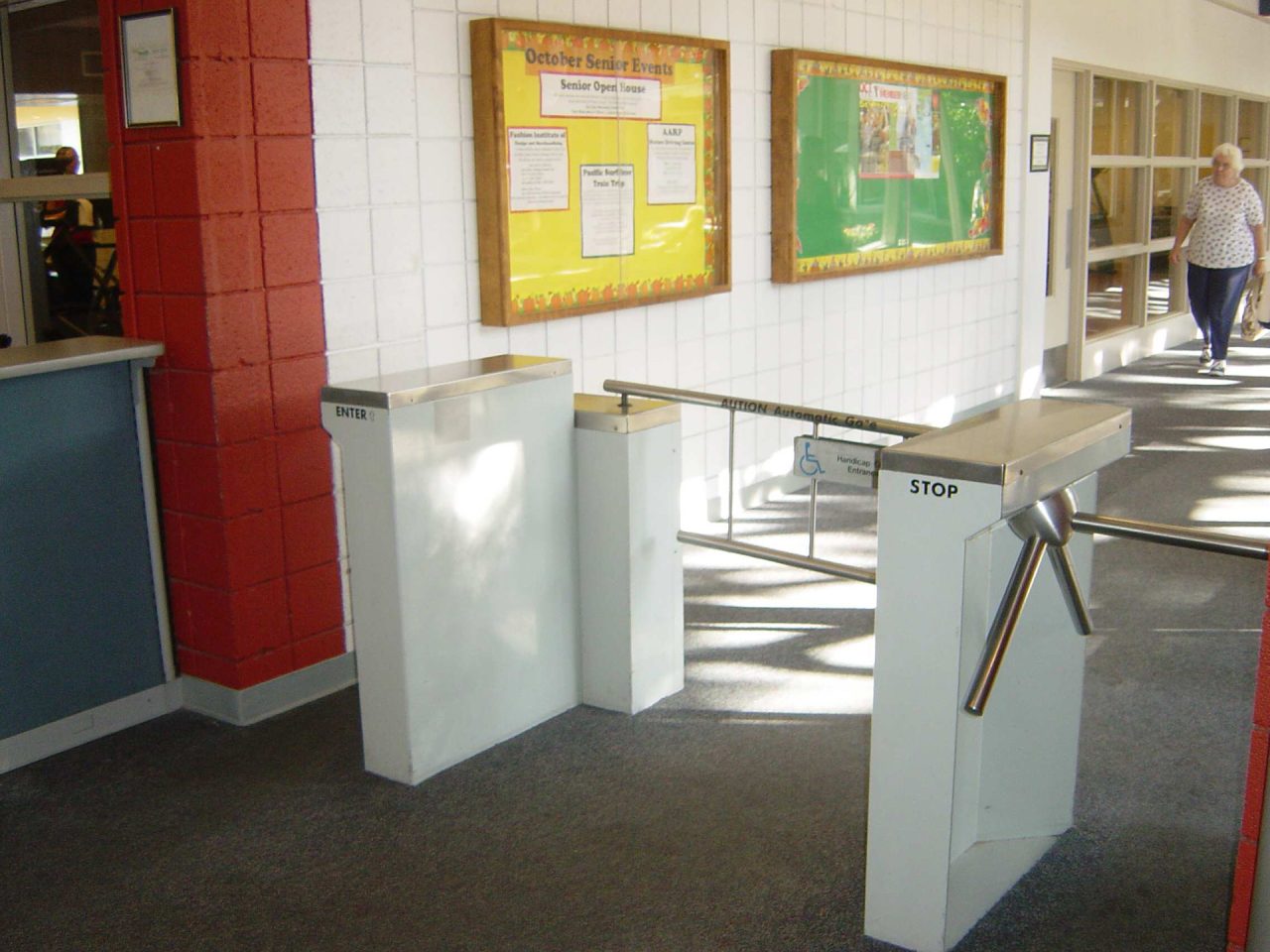 Waist-high mechanical turnstile controlling pedestrian access in a facility hallway
