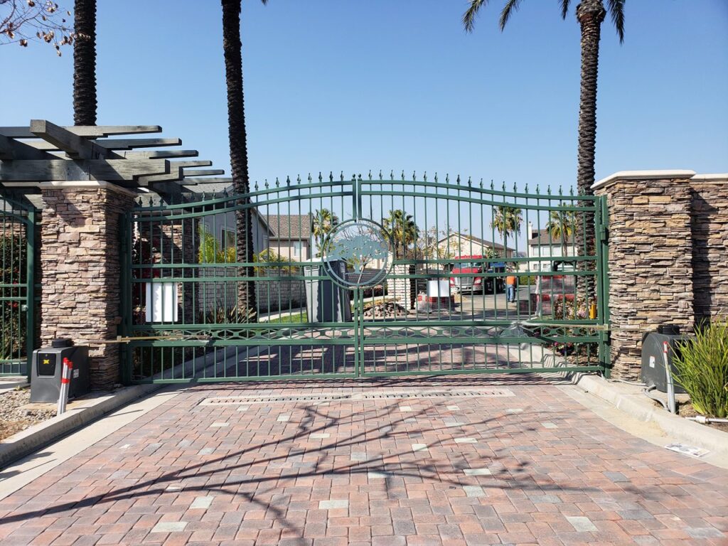 Ornamental iron vehicle gate at a landscaped commercial campus entrance