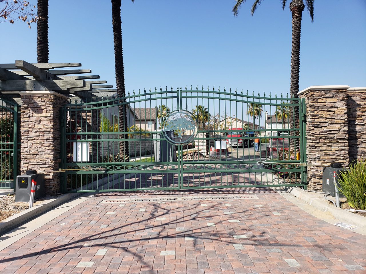 Ornamental iron vehicle gate at a landscaped commercial campus entrance